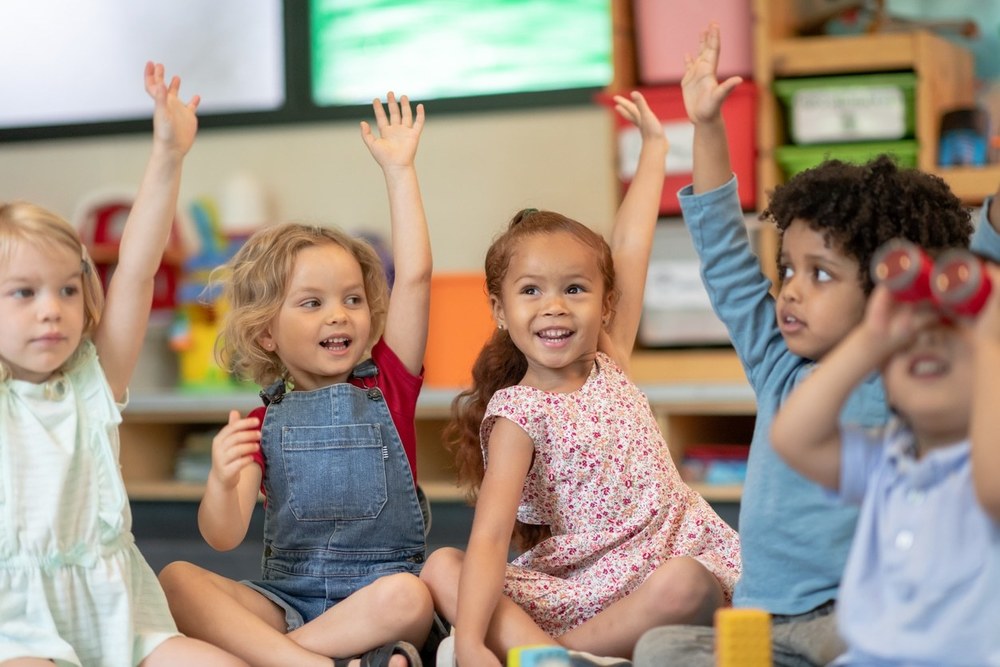 Preschool students raising their hands